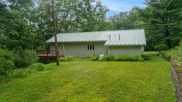 back of house with metal roof, a lawn, and a wooden deck