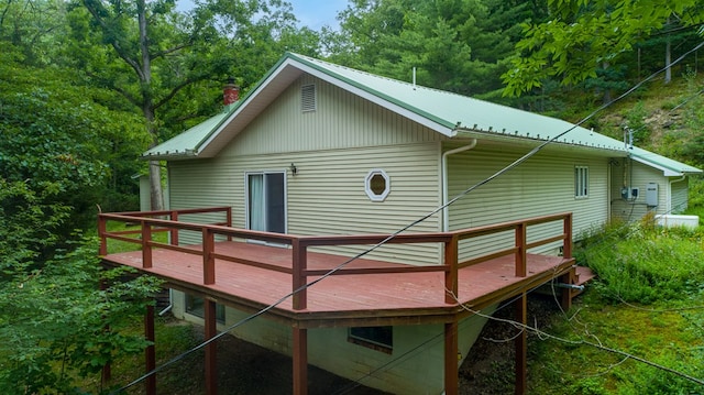 rear view of property with metal roof, a deck, and a chimney