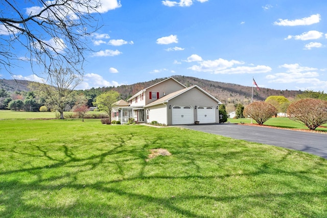 view of home's exterior with a lawn, an attached garage, driveway, and a mountain view