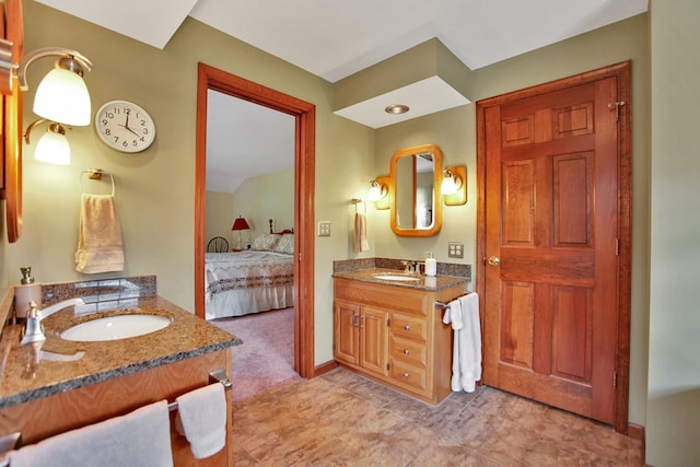 ensuite bathroom with two vanities, ensuite bath, baseboards, and a sink