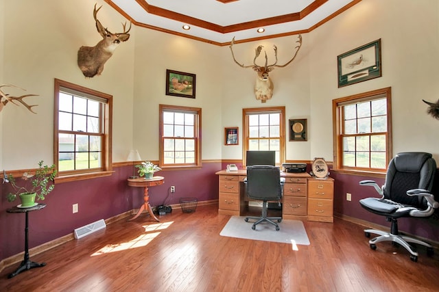 home office featuring a high ceiling, wood finished floors, visible vents, ornamental molding, and baseboards