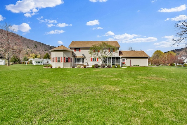rear view of property featuring a mountain view and a yard