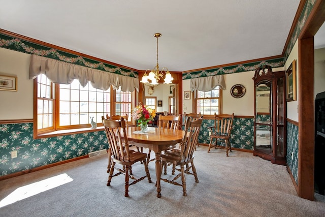 dining space featuring crown molding, carpet flooring, and a notable chandelier