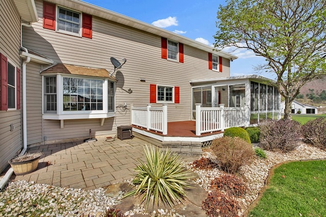 rear view of house with a patio area, a sunroom, and a deck
