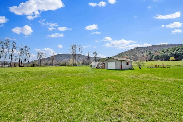 view of yard with an outdoor structure, a mountain view, a rural view, and a garage