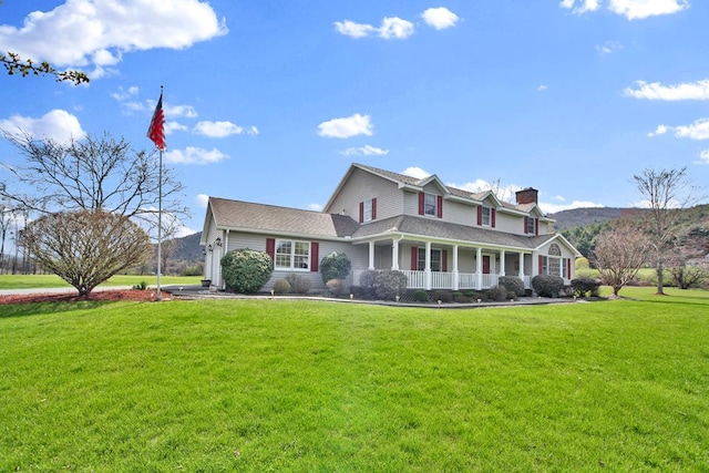 view of front of property featuring a chimney, a front lawn, and covered porch