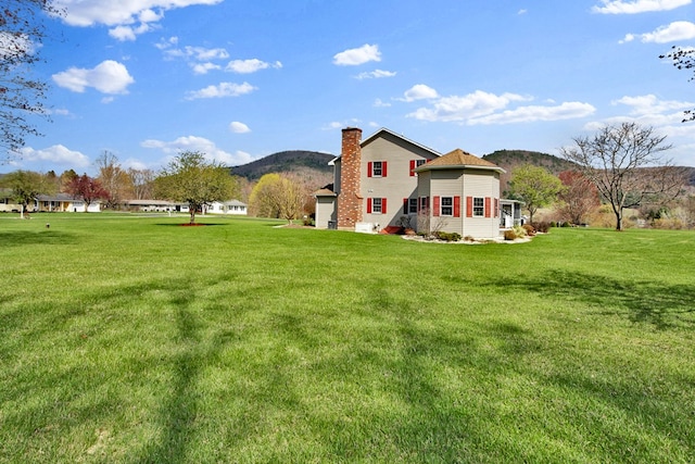 back of property featuring a lawn, a chimney, and a mountain view