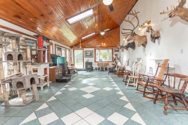 interior space with wooden ceiling, a wood stove, high vaulted ceiling, a skylight, and ceiling fan