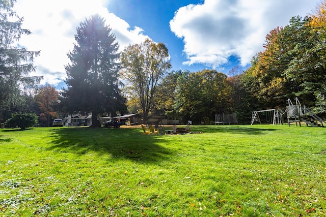 view of yard with a playground and a trampoline