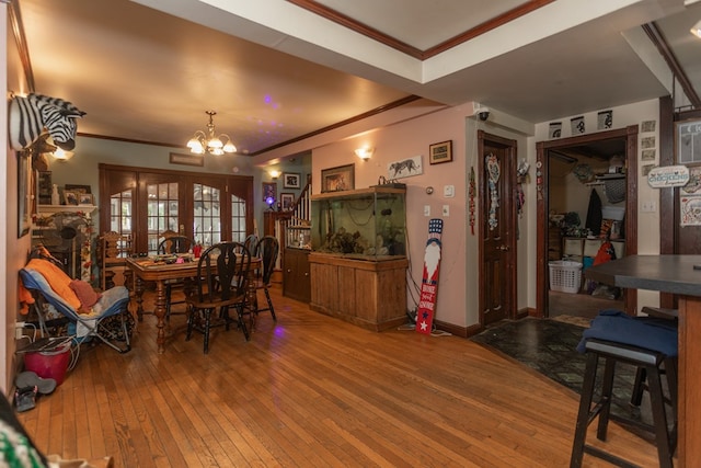 dining room with a fireplace, hardwood / wood-style floors, ornamental molding, and a notable chandelier