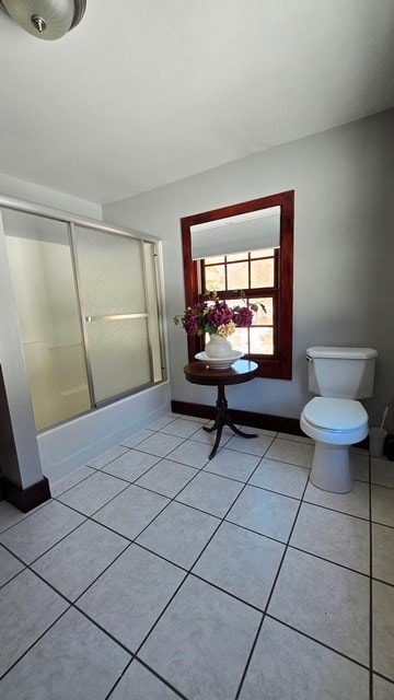 bathroom with toilet, tile patterned flooring, and combined bath / shower with glass door