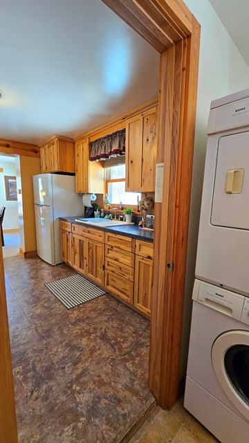 kitchen with white refrigerator, stacked washing maching and dryer, and sink