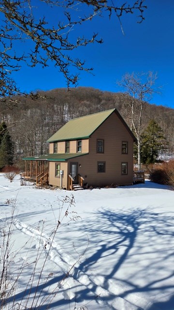 snow covered rear of property featuring a mountain view