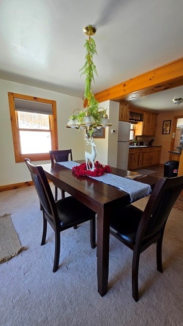 dining room featuring light carpet and beam ceiling