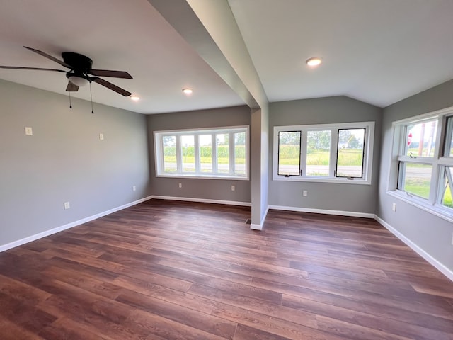 spare room featuring dark wood finished floors, lofted ceiling, baseboards, and a wealth of natural light