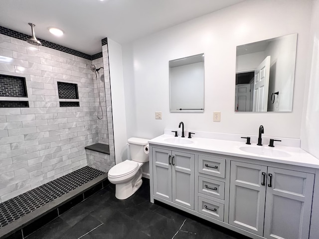 full bath with double vanity, a tile shower, toilet, and a sink