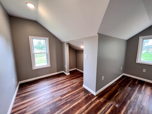 bonus room featuring dark wood finished floors, vaulted ceiling, and baseboards