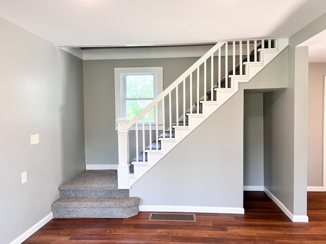 staircase with visible vents, baseboards, and wood finished floors