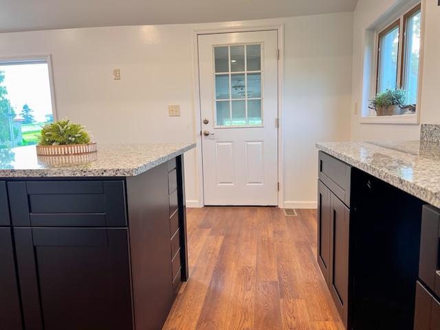 kitchen featuring light stone counters, baseboards, a wealth of natural light, and wood finished floors