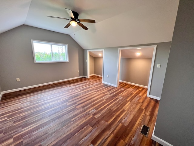 additional living space with visible vents, dark wood-type flooring, baseboards, and vaulted ceiling