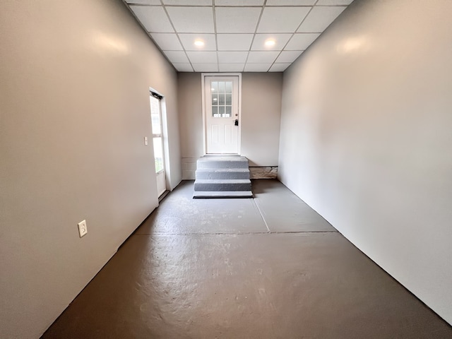 corridor featuring finished concrete flooring and a paneled ceiling