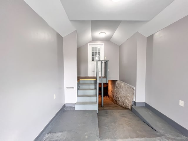 stairs featuring unfinished concrete flooring and lofted ceiling