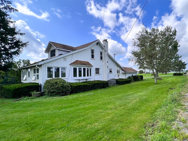 back of property with a chimney and a yard