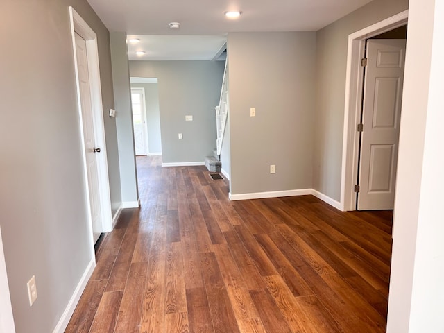 corridor with baseboards and dark wood-style floors