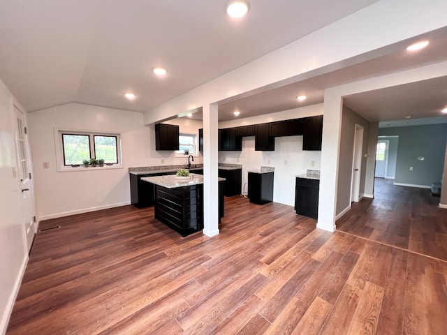 kitchen with a sink, dark cabinetry, baseboards, and dark wood-style flooring