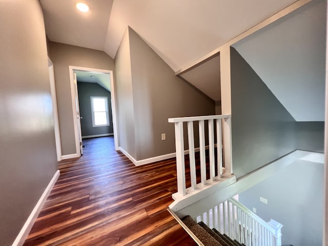 staircase featuring baseboards, lofted ceiling, and wood finished floors