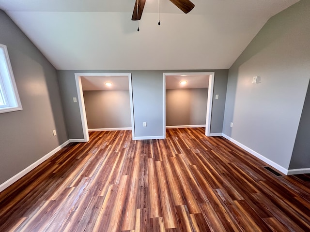 unfurnished bedroom with visible vents, baseboards, dark wood finished floors, ceiling fan, and vaulted ceiling