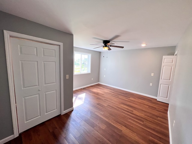 empty room with a ceiling fan, dark wood-type flooring, and baseboards