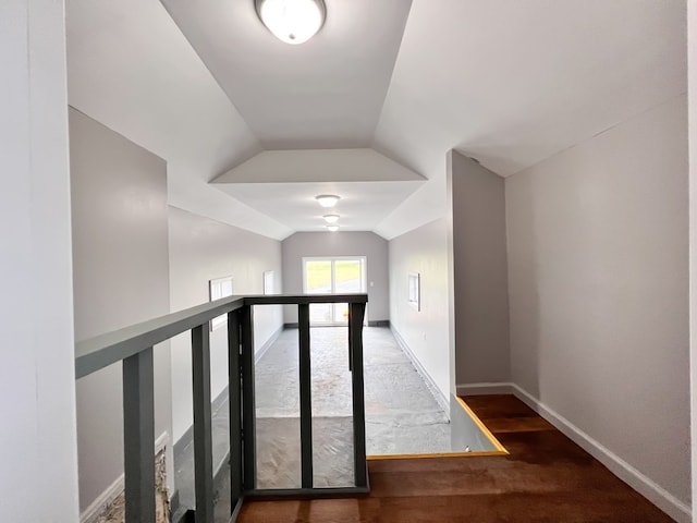 corridor featuring vaulted ceiling and baseboards