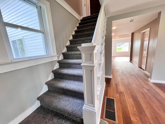 stairway with visible vents, baseboards, and wood finished floors