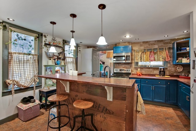 kitchen with appliances with stainless steel finishes, a breakfast bar, blue cabinetry, and tasteful backsplash