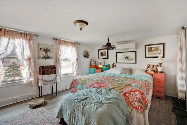 bedroom featuring baseboards, an AC wall unit, and wood finished floors