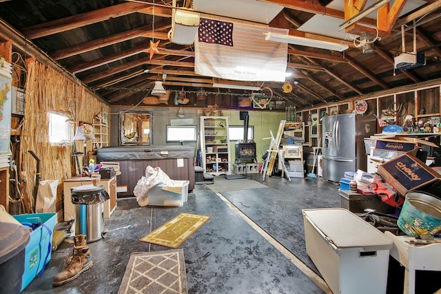 garage with a garage door opener and stainless steel refrigerator with ice dispenser