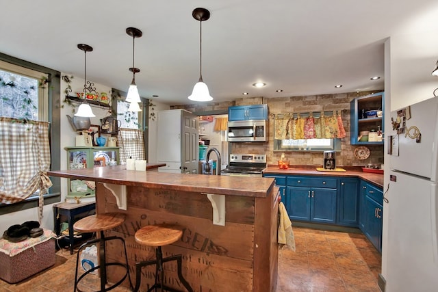 kitchen with blue cabinetry, backsplash, appliances with stainless steel finishes, and a kitchen breakfast bar