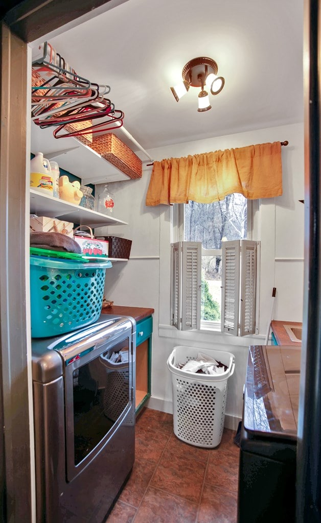 clothes washing area with laundry area, dark tile patterned floors, and washer and clothes dryer