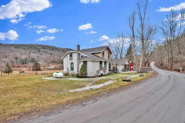 view of front of home featuring a front yard, driveway, and a chimney