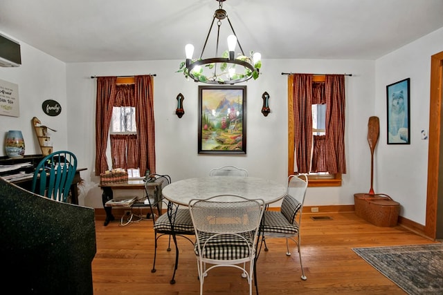 dining area with baseboards, wood finished floors, and an inviting chandelier