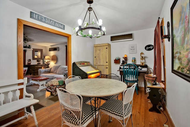 dining area featuring wood-type flooring, baseboards, a notable chandelier, and a wall mounted AC