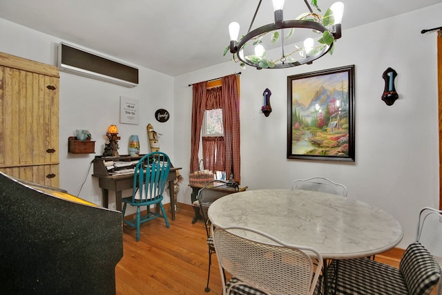 dining area with light wood-style floors, a chandelier, and a wall mounted AC