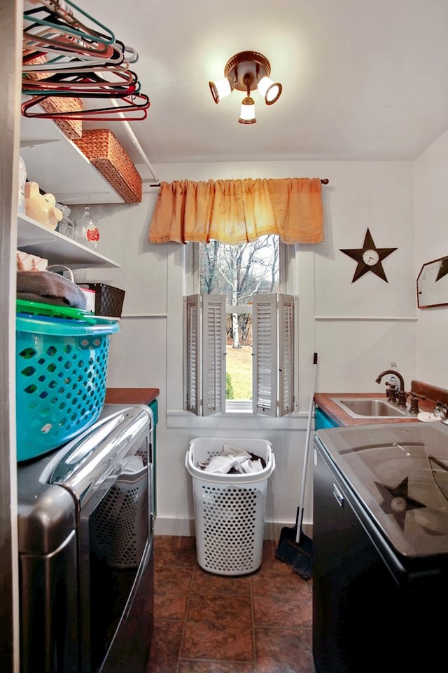 laundry area featuring a sink, laundry area, dark tile patterned flooring, and washing machine and clothes dryer