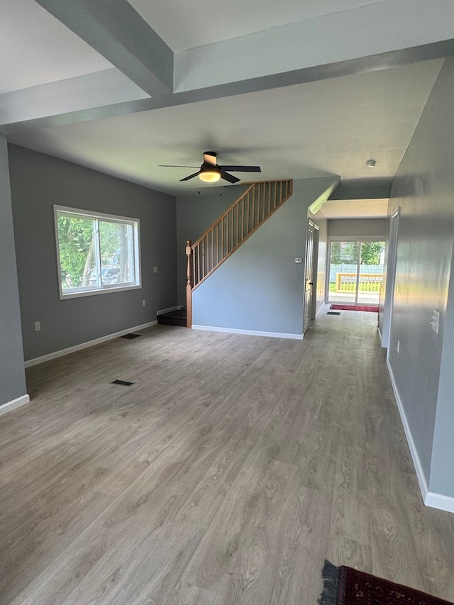 121 Park Pl, Waverly, NY 14892 - unfurnished living room featuring healthy amount of natural light, wood finished floors, a ceiling fan, and stairway