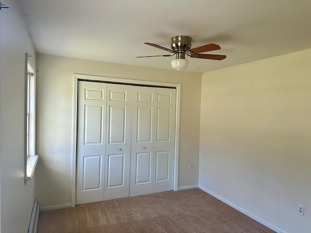 unfurnished bedroom with baseboard heating, ceiling fan, a closet, and carpet floors