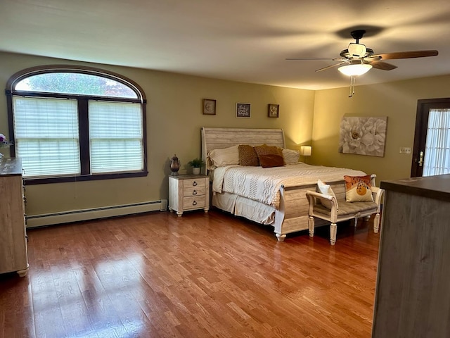 unfurnished bedroom with hardwood / wood-style flooring, ceiling fan, multiple windows, and a baseboard heating unit