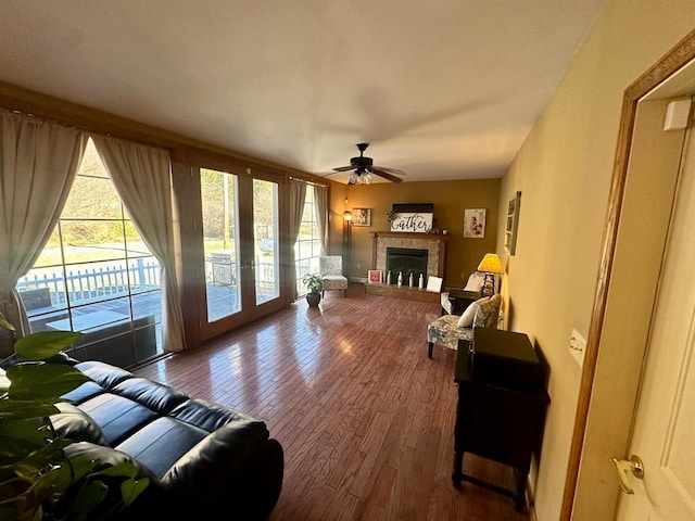 living room featuring ceiling fan, a fireplace, wood-type flooring, and french doors