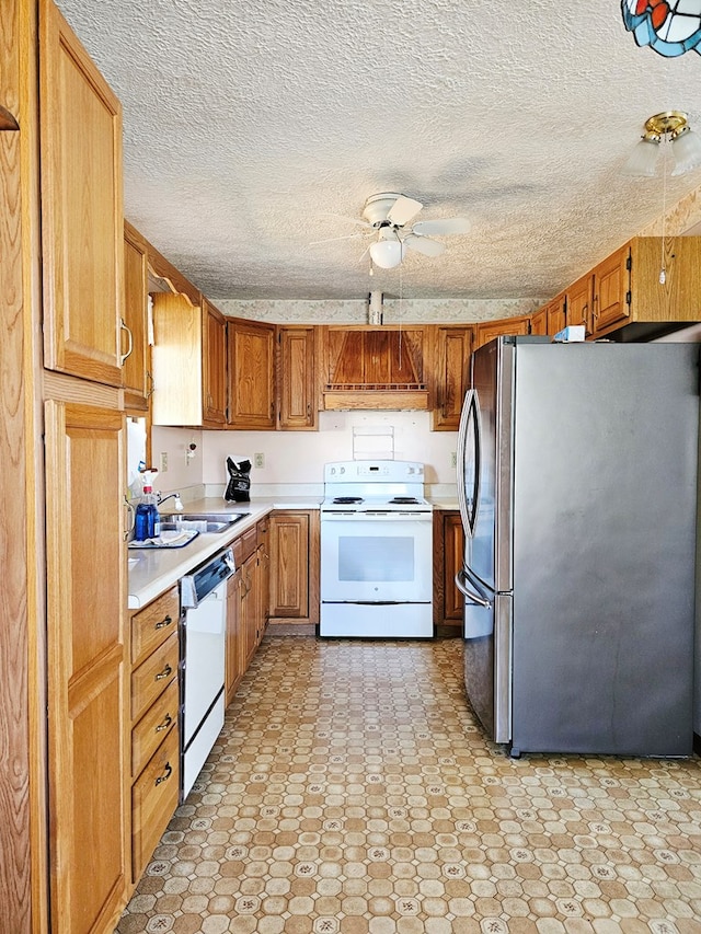 kitchen with white appliances, ceiling fan, light countertops, brown cabinets, and a sink