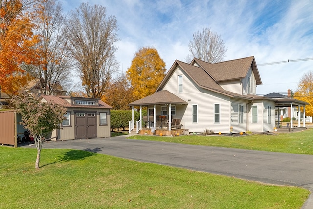 view of front facade featuring a front lawn, a porch, and a storage shed